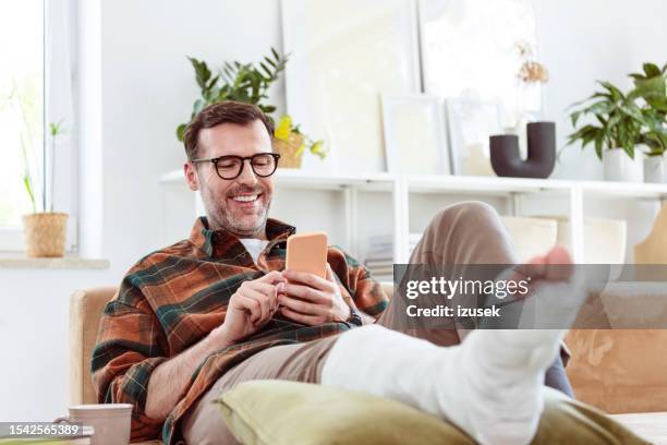 homme mûr avec jambe cassée à la maison - jambe photos et images de collection