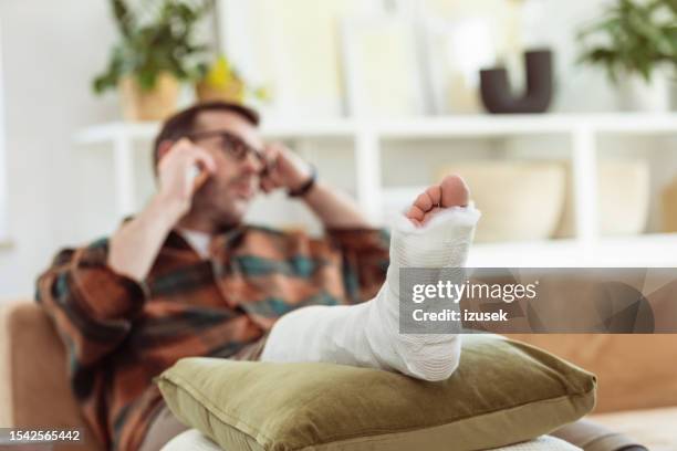 worried mature man with broken leg at home - broken leg stock pictures, royalty-free photos & images