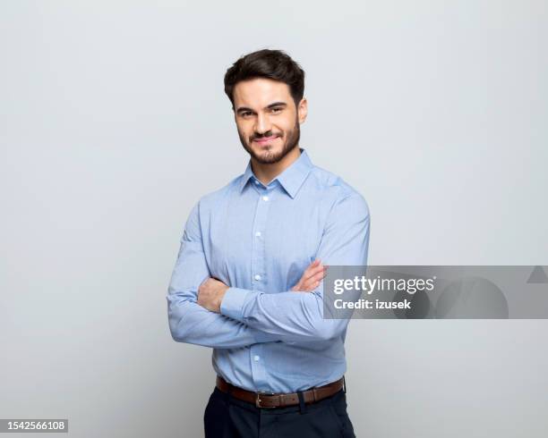 joven hombre de negocios sonriendo a la cámara - brazos cruzados negocios fotografías e imágenes de stock