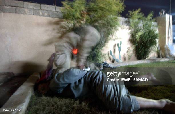 Soldier from the 1st Battalion, 22nd Regiments of the 4th Infantry Division ties an Iraqi detainee during a raid in former Iraqi dictator Saddam...