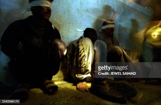 Soldiers from the 1st Battalion, 22nd Regiments of the 4th Infantry Division ask question blindfolded Iraqi detainees during a raid in former Iraqi...