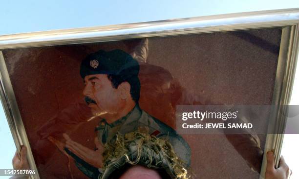 Soldier from the 1st Battalion, 22nd Infantry Regiment of the 4th Infantry Division carries a huge picture of former Iraqi dictator Saddam Hussein on...