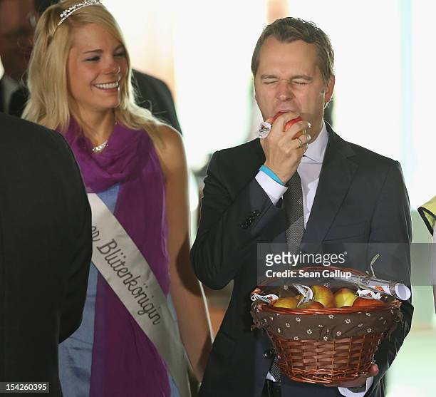 German Health Minister Daniel Bahr, after pronouncing in English: "An apple a day keeps the doctor away," bites into an apple after receiving it from...