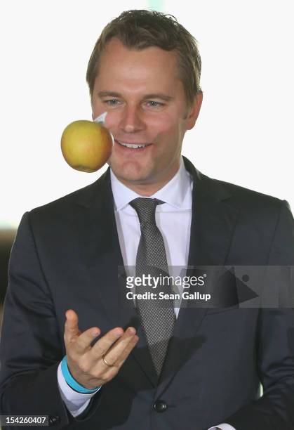 German Health Minister Daniel Bahr, after pronouncing in English: "An apple a day keeps the doctor away," tosses an apple into the air after...