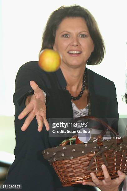 German Agriculture and Consumer Protection Minister Ilse Aigner tosses an apple to photographers after receiving a bsket from regional Harvest Queens...