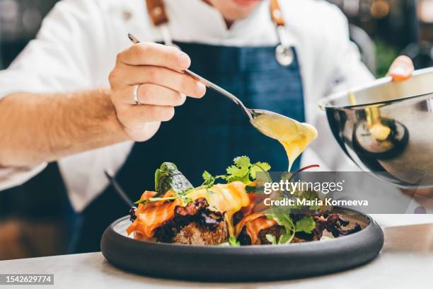close up image of a chef preparing a gourmet dish. chef is decorating the plate just before the serving. - servicio de calidad fotografías e imágenes de stock