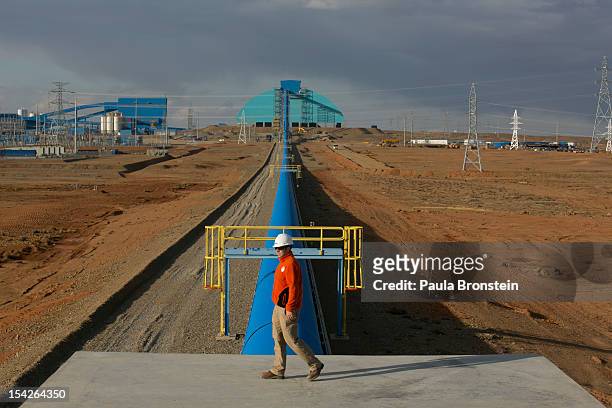 Worker walks by the blue conveyor belt that moves rock from the crusher to the concentrator area at the Oyu Tolgoi mine October 11, 2012 in the south...