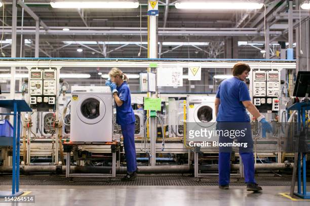 Employees check washing machine units for quality control on the production line at the Electrolux AB plant in Olawa, Poland, on Tuesday, Oct. 16,...