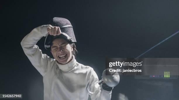 female fencer removing face guard and cheering. celebrating victory - fencing stock pictures, royalty-free photos & images