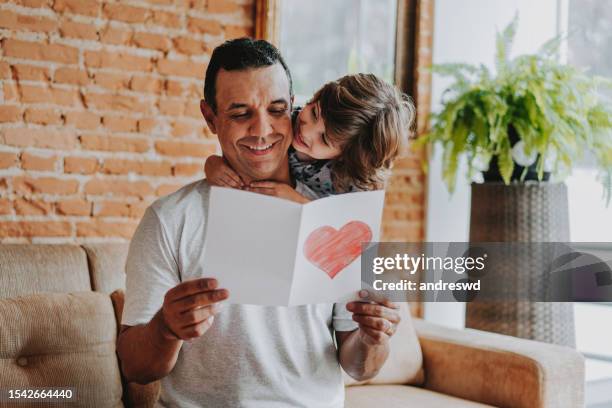 son handing postcard to father on father's day - man handing paper stock pictures, royalty-free photos & images