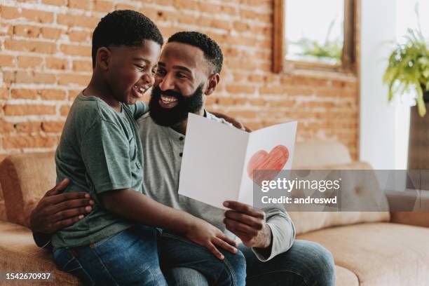 son handing postcard to father on father's day - happy birthday postcards stock pictures, royalty-free photos & images