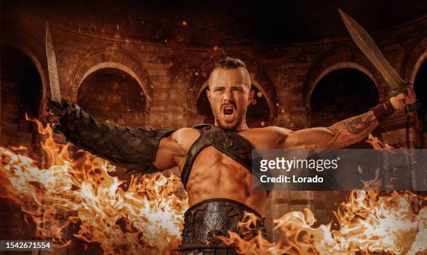 a warrior roman gladiator holding a weapon in a fiery colosseum setting - gladiator armour stock pictures, royalty-free photos & images