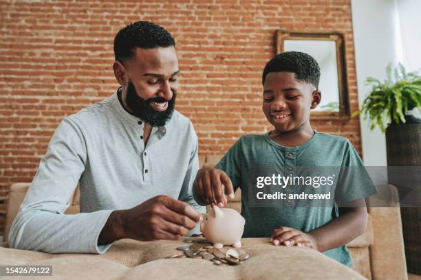 father and son coin bank - savings stock pictures, royalty-free photos & images