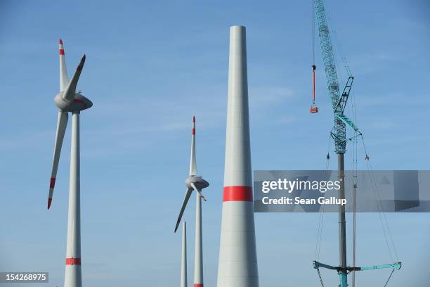 Workers standing in a basket hang from a crane next to a wind turbine under construction at the Werder/Kassin RH2-WKA windpark on October 17, 2012...