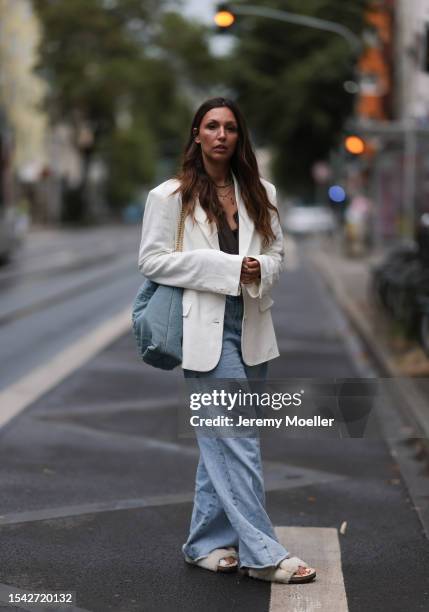 Kira Bejaoui wearing white linen blazer, blue top and black lace bra underneath, Gucci logo belt, wide leg pair of jeans, fluffy sandals and denim...