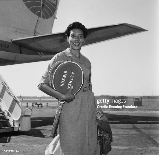 American tennis player Althea Gibson carrying tennis rackets with personalised covers on arrival at London Airport, June 22nd 1959. The reigning...