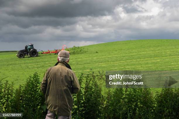 senior man watching a tractor in a field - waxed jacket stock pictures, royalty-free photos & images