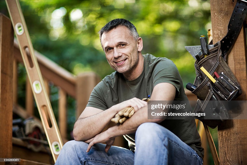 Happy Male Carpenter With Work Gloves And Tool Belt.