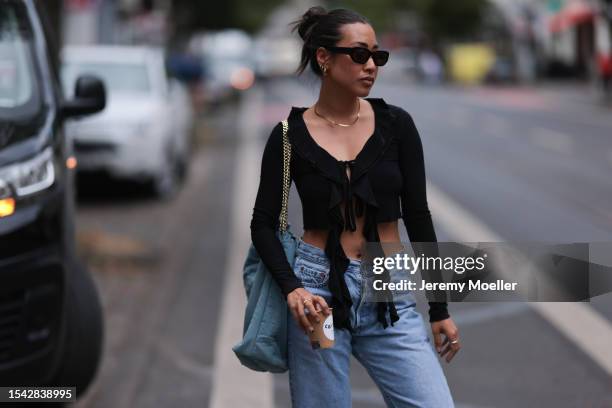 Thi Nguyen wearing black sunnies, gold earrings, rings and necklace, black cropped tied top, denim Ariane Ernst bag, high waisted denim pair of jeans...