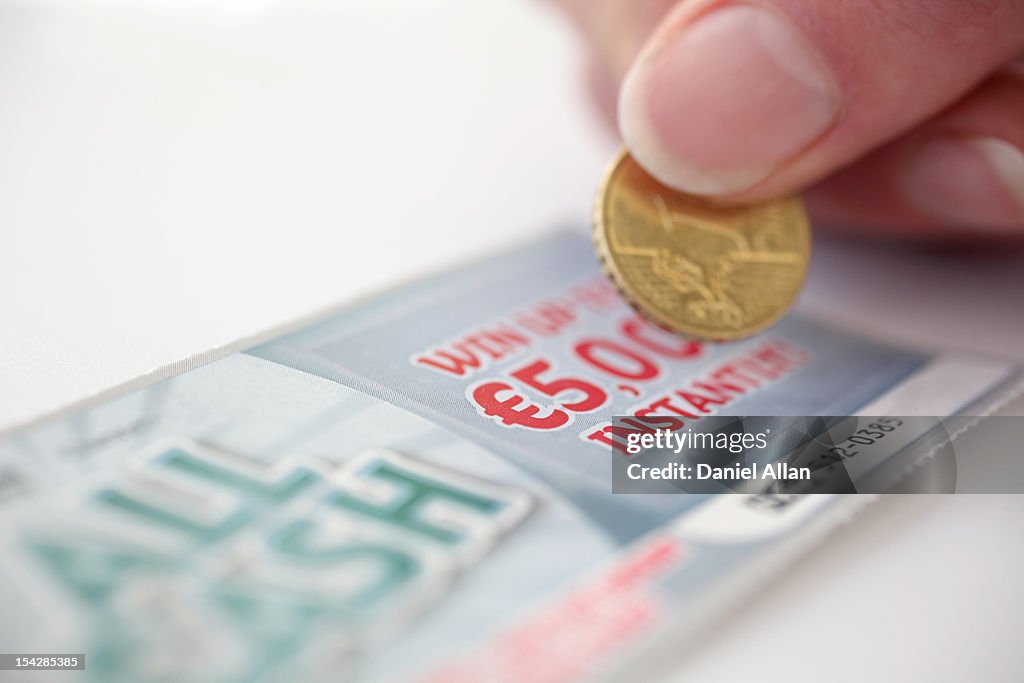 Coin scratching a lottery scratch card