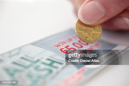 Coin scratching a lottery scratch card Coin scratching a lottery scratch card