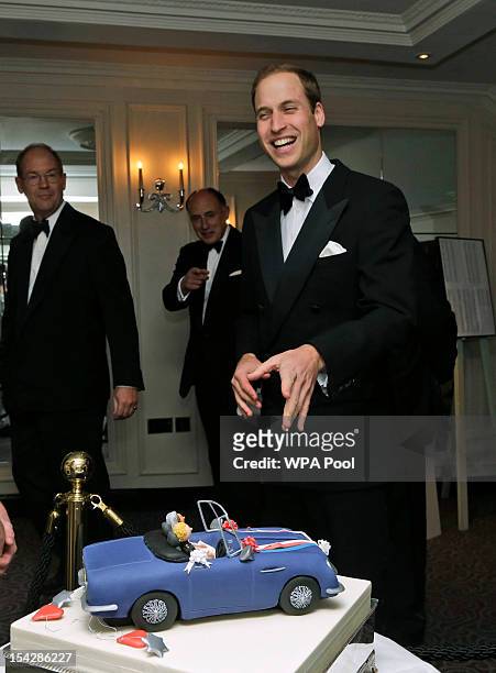 Prince William, Duke of Cambridge and Patron of St Giles Trust laughs as he walks past a special cake re-enacting the scene from his wedding in 2011...