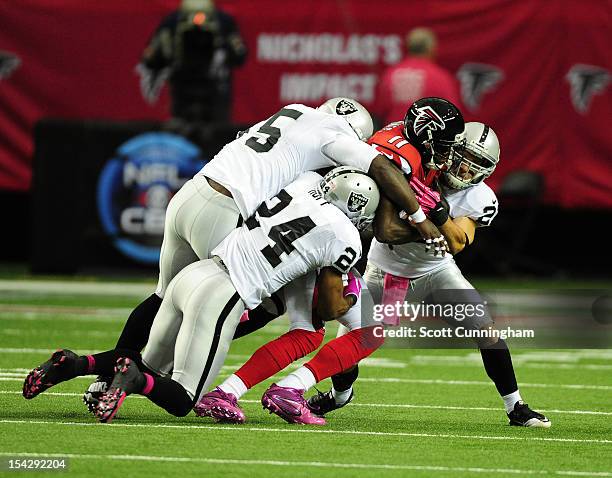 Julio Jones of the Atlanta Falcons is tackled by Michael Huff, Rolando McClain, and Matt Giordano of the Oakland Raiders at the Georgia Dome on...