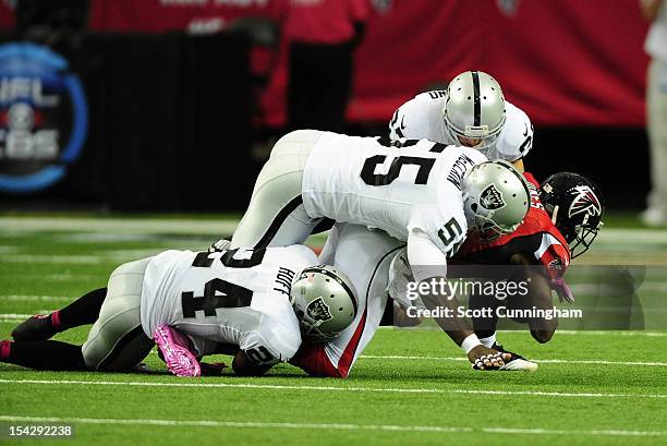 Julio Jones of the Atlanta Falcons is tackled by Michael Huff, Rolando McClain, and Matt Giordano of the Oakland Raiders at the Georgia Dome on...