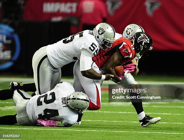 Julio Jones of the Atlanta Falcons is tackled by Michael Huff, Rolando McClain, and Matt Giordano of the Oakland Raiders at the Georgia Dome on...