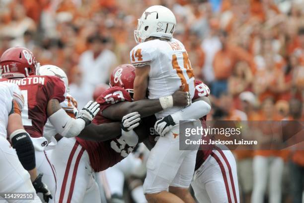Defensive tackle Casey Walker and defensive end Chuka Ndulue of the Oklahoma Sooners hit quarterback David Ash of the Texas Longhorns on October 13,...