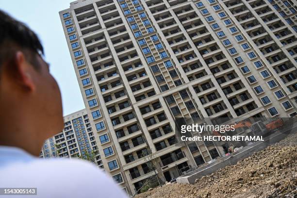 This picture taken on June 2, 2023 shows homebuyer Wang, using a pseudonym, looking at a building under construction in the compound where he bought...