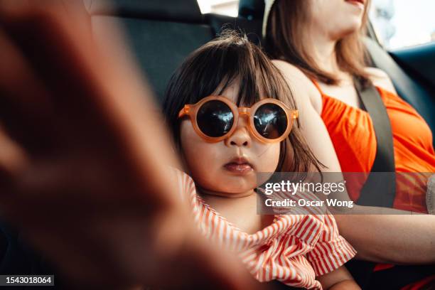 asian little girl with sunglasses in a taxi with her mother - guay fotografías e imágenes de stock