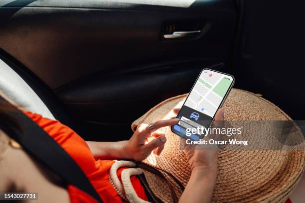 close-up of young woman using smartphone while sitting at the back seat of a taxi - taxi españa stockfoto's en -beelden