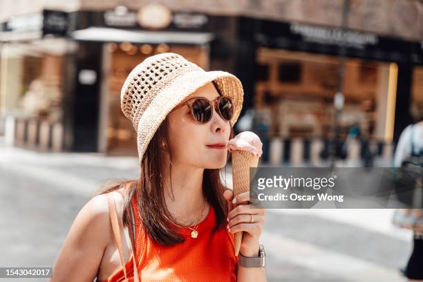 female tourist eating ice cream cone on the street - sf stock pictures, royalty-free photos & images
