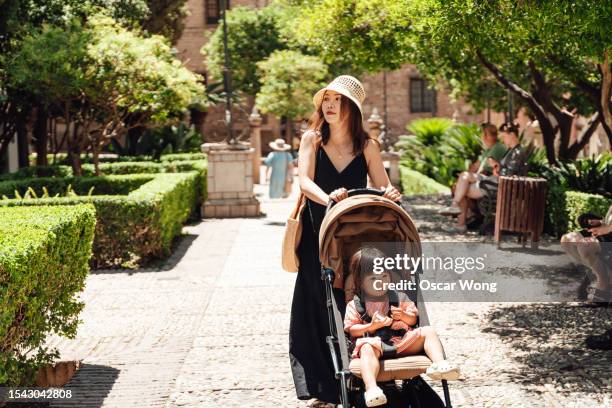 young asian mother pushing a stroller, walking in the park - carrinho de criança imagens e fotografias de stock