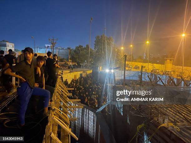 Protesters stand on top of a building overlooking a street full of Iraqi riot policemen leading to the Swedish embassy in Baghdad on July 20, 2023.