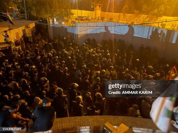 Protesters sit on top of a building next to the Swedish embassy in Baghdad on July 20, 2023. Iraq condemned the torching of Sweden's embassy in...