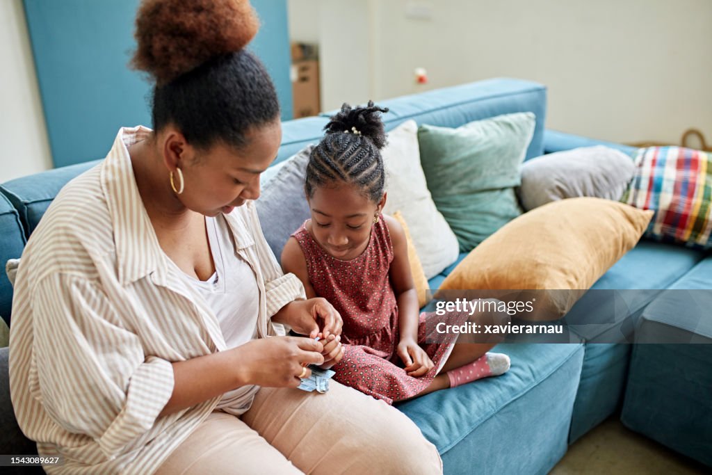 Mãe negra cuidando do diabetes da filha pequena