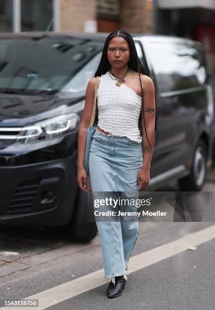 Guest wearing white structured and asymmetric top, different big type of necklaces with snails and leave optic, denim Ariane Ernst bag, wide maxi...