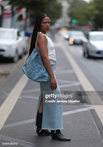 Guest wearing white structured and asymmetric top, different big type of necklaces with snails and leave optic, denim Ariane Ernst bag, wide maxi...