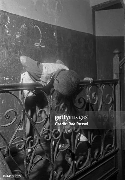 Young children leaning over the metalwork balustrade of the stairwell in a property at a social housing development on Henry Street in the Lower East...
