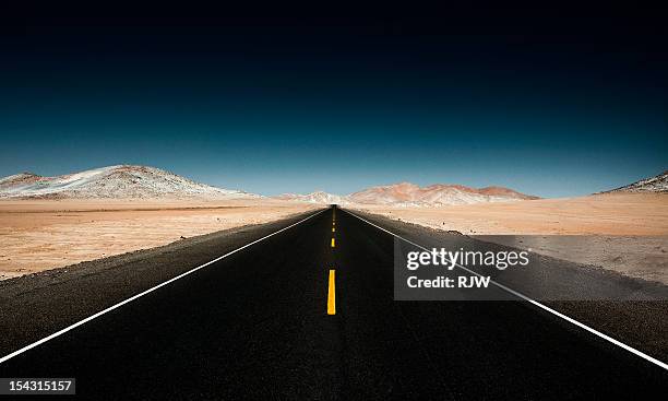 endless straight road through desert mountains - unendlichkeit stock-fotos und bilder