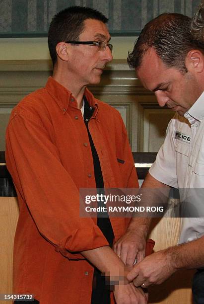 Policeman removes the handcuffs of Frantz Diguelman, the lover of a Madagascan woman who allegedly tricked him into killing her husband with a...