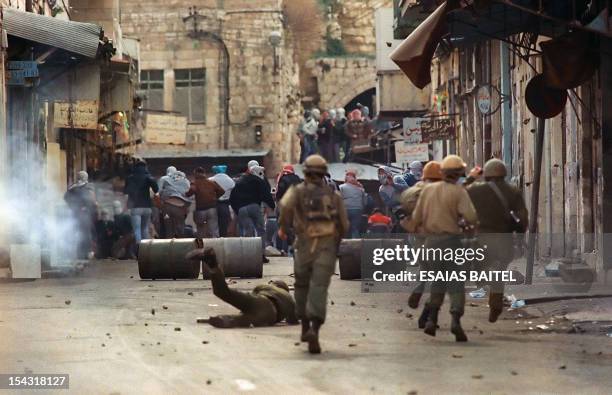 Israeli soldier falls to the ground 29 January 1988 in Nablus after he was hit and wounded by a metal ball fired from a sling-shot by a Palestinian...