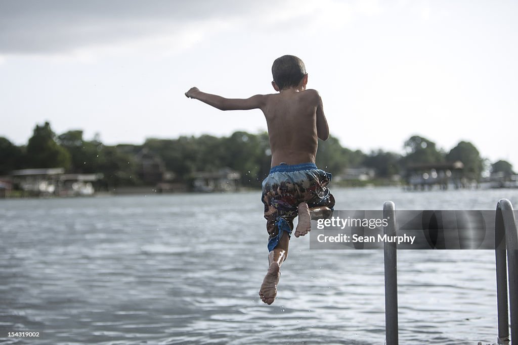 Young boy jumping into lake off of a dock