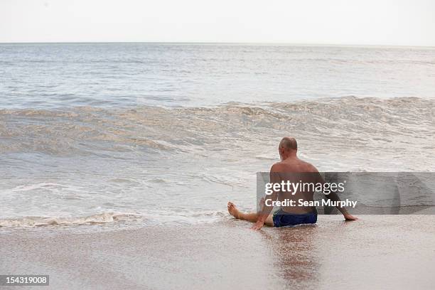 man sitting in the sand at the ocean - jacksonville beach stock pictures, royalty-free photos & images