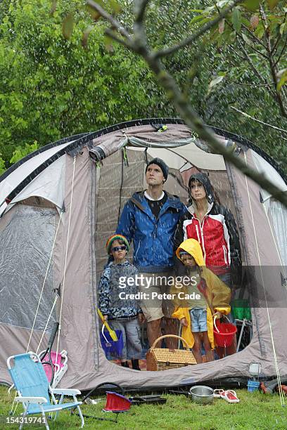 family looking out from tent at rain - tent stock pictures, royalty-free photos & images