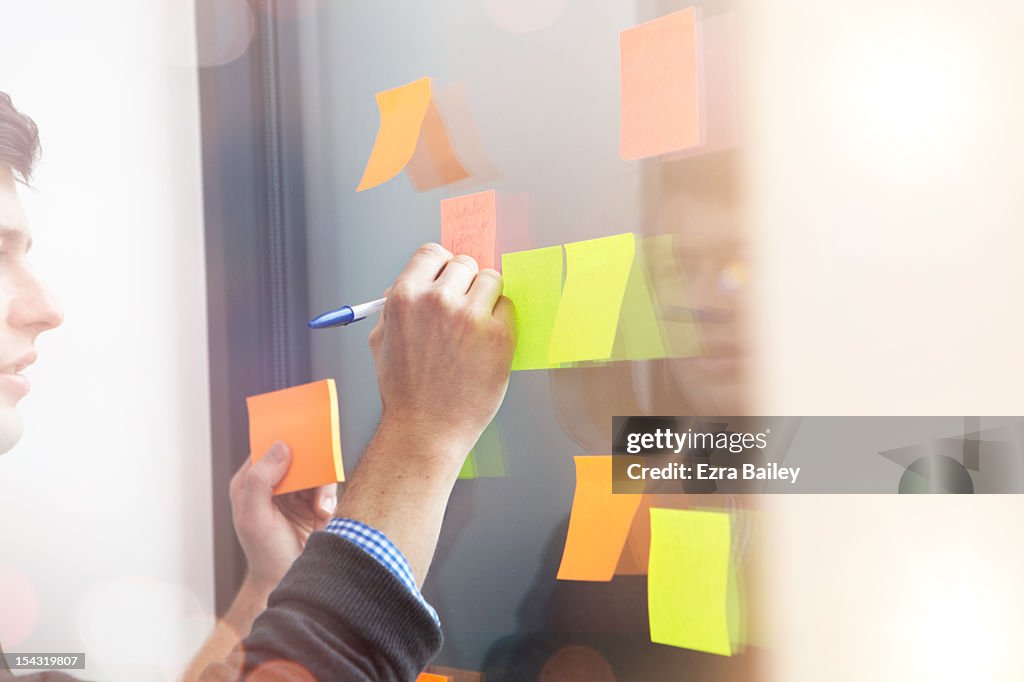 Businessman writing on a sticky note.