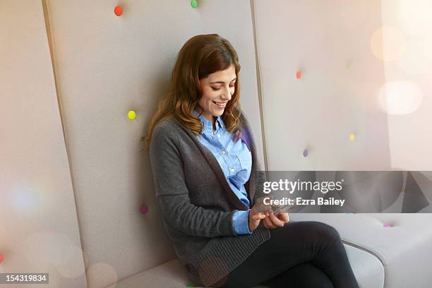 woman smiling and using her mobile phone. - strickjacke stock-fotos und bilder