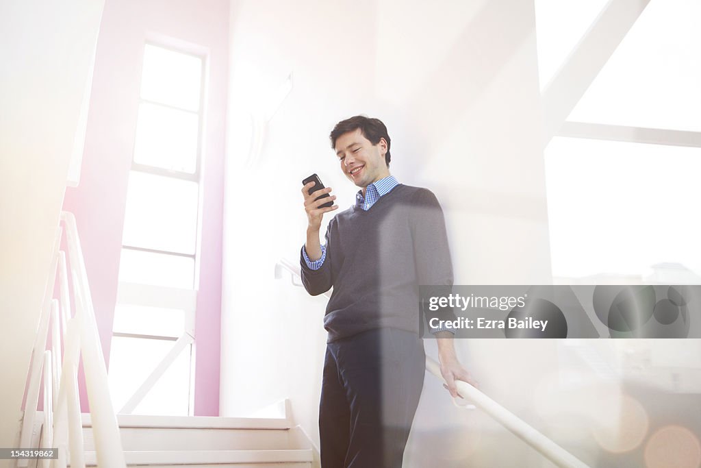 Businessman checking his phone of the stairs.